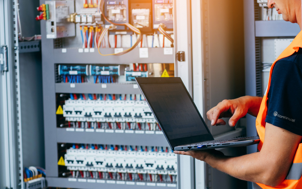 Person holding laptop near electric panel